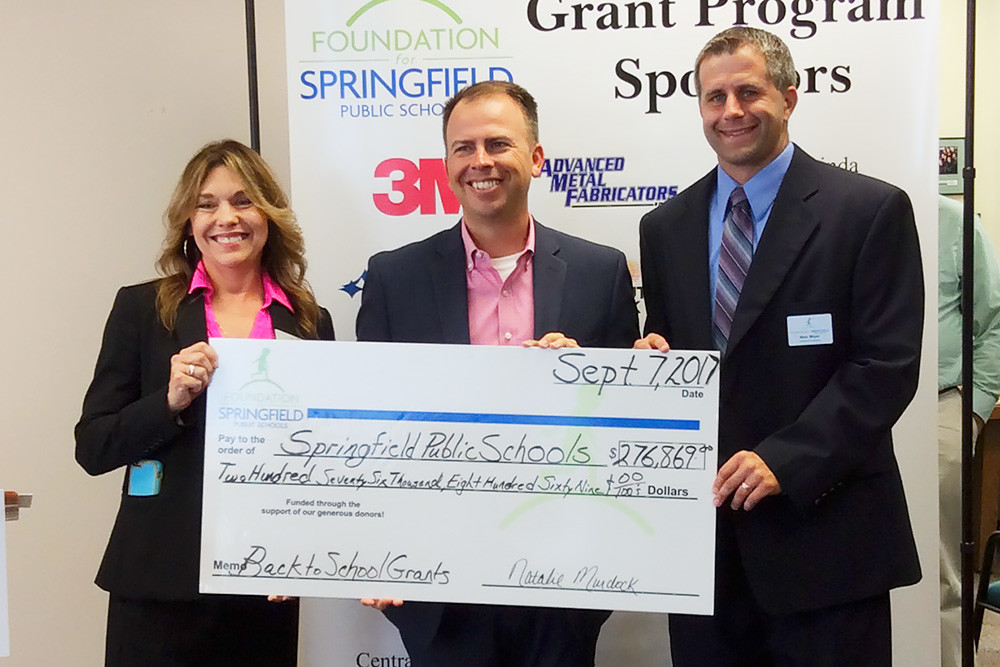 Foundation for Springfield Public Schools Director of Development Pamela Anderson, far left, and board President-elect Marc Mayer deliver a check to SPS Superintendent John Jungmann, middle.