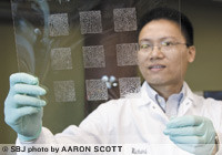Siqiang 'Richard' Zhu, Ph.D., checks a test print of Crosslink's polymer gel on a plastic sheet. The polymer gel is applied via a screenprint in the same method as printed T-shirts.