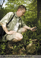 John Curtis, a Springfield optometrist, uses a hand-held GPS to locate a geocache hidden under rocks and sticks near the Wilson's Creek Greenway. He estimates that there are more than 400 geocaches hidden in a 20-mile radius from Missouri State University.