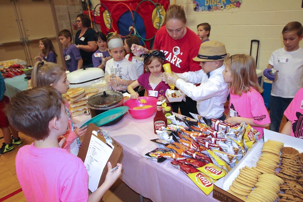 LUNCH BREAK
Above, Ozark East second-graders take orders at a restaurant hosted by the school. The culmination of an economics unit, students learned about running a business from local bankers and a former McDonald’s franchise owner before running the restaurant April 18.