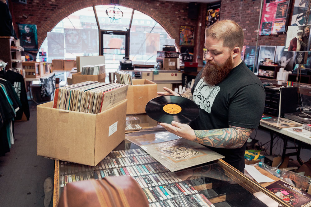 BUSINESS SUPPORT: Manager Erik Milan organizes albums at Stick It In Your Ear. Store owner Wes Nichols signed a pledge in support of increasing Missouri’s minimum wage.