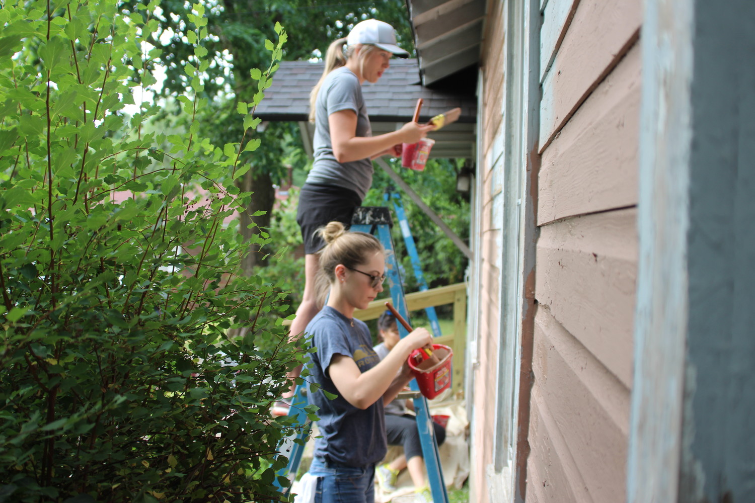 Volunteers paint a home in Woodland Heights during a June Rock the Block neighborhood cleanup event.