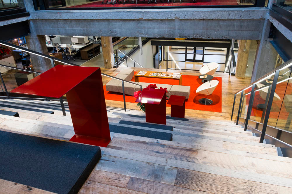 Reclaimed
The top of the staircase on the third floor looks down on a seating area. The flooring is reclaimed barn wood by Ozarkaeology Inc. and modern red desks splash color along the stairs. Kansas City architect Matthew Hufft created the look.