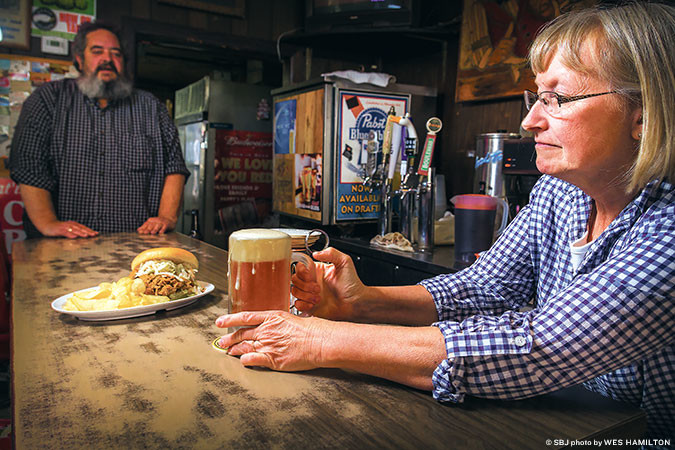 COMMUNITY CONNECTION: Pappy’s waitress Debra Keese serves up a cold beer and a smoked pork sandwich. Her husband, Scott, co-owns the Grant Beach establishment.