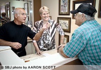 Manoli Savvenas, left, and Valerie Savvenas, talk with customer Frank Shinn about repairing a broken necklace at Manoli's Jewelers. Manoli Savvenas says conducting business in the Ozarks is more fruitful than in his native Greece.