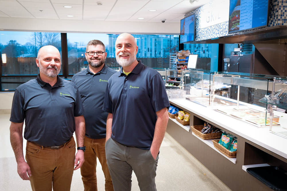 NETWORK ROOTS: J.J. Martin, Rick Manweiler and Jeff Dixon, left to right, of Techtree Partners stand in Mercy Hospital’s new cafeteria. The firm spent 18 months installing the electronic menu boards, security cameras and other network systems.