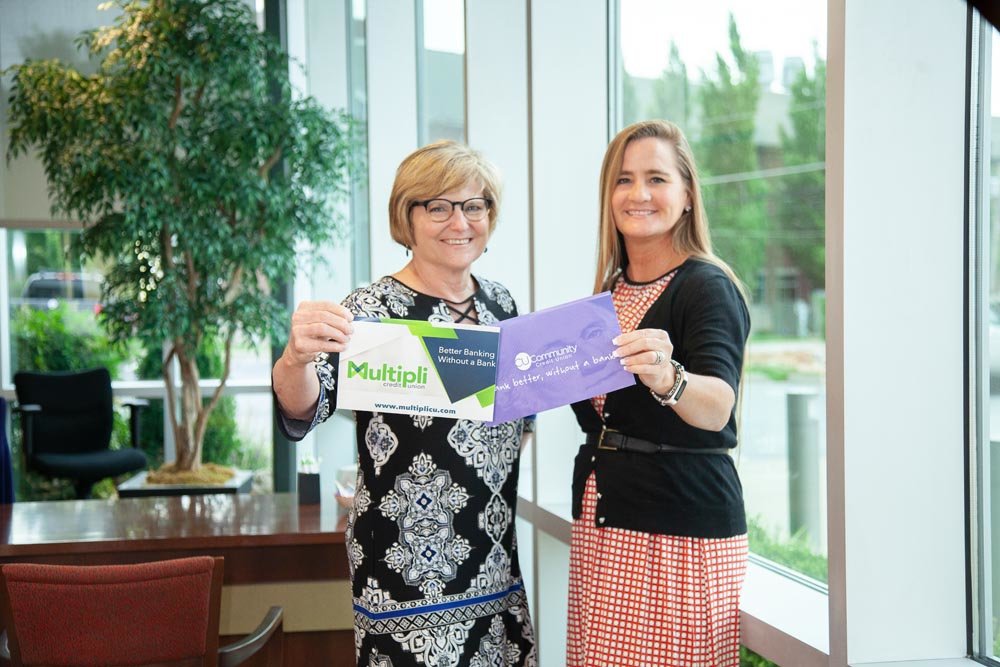STATEMENT PIECE: Judy Hadsall, left, holds a flyer for the rebranded Multipli Credit Union, and Alisa Lawler contrasts the change with a CU Community Credit Union promotional piece. Credit unions are revamping their messaging.