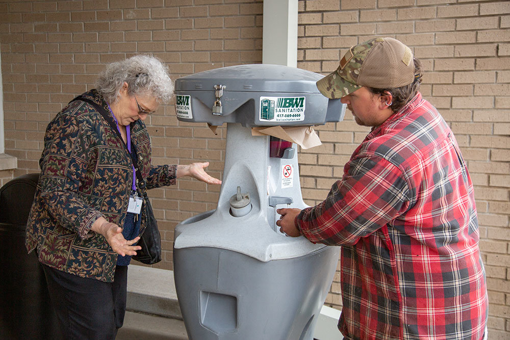 STAY CLEAN: A hand-washing station outside the entrance of Burrell Behavioral Health is a sign of the times during the coronavirus outbreak. Alex Schweidel, at right, of Carson's Nurseries and Dr. Penelope McAlmond-Ross sanitize their hands before entering the building March 17.
