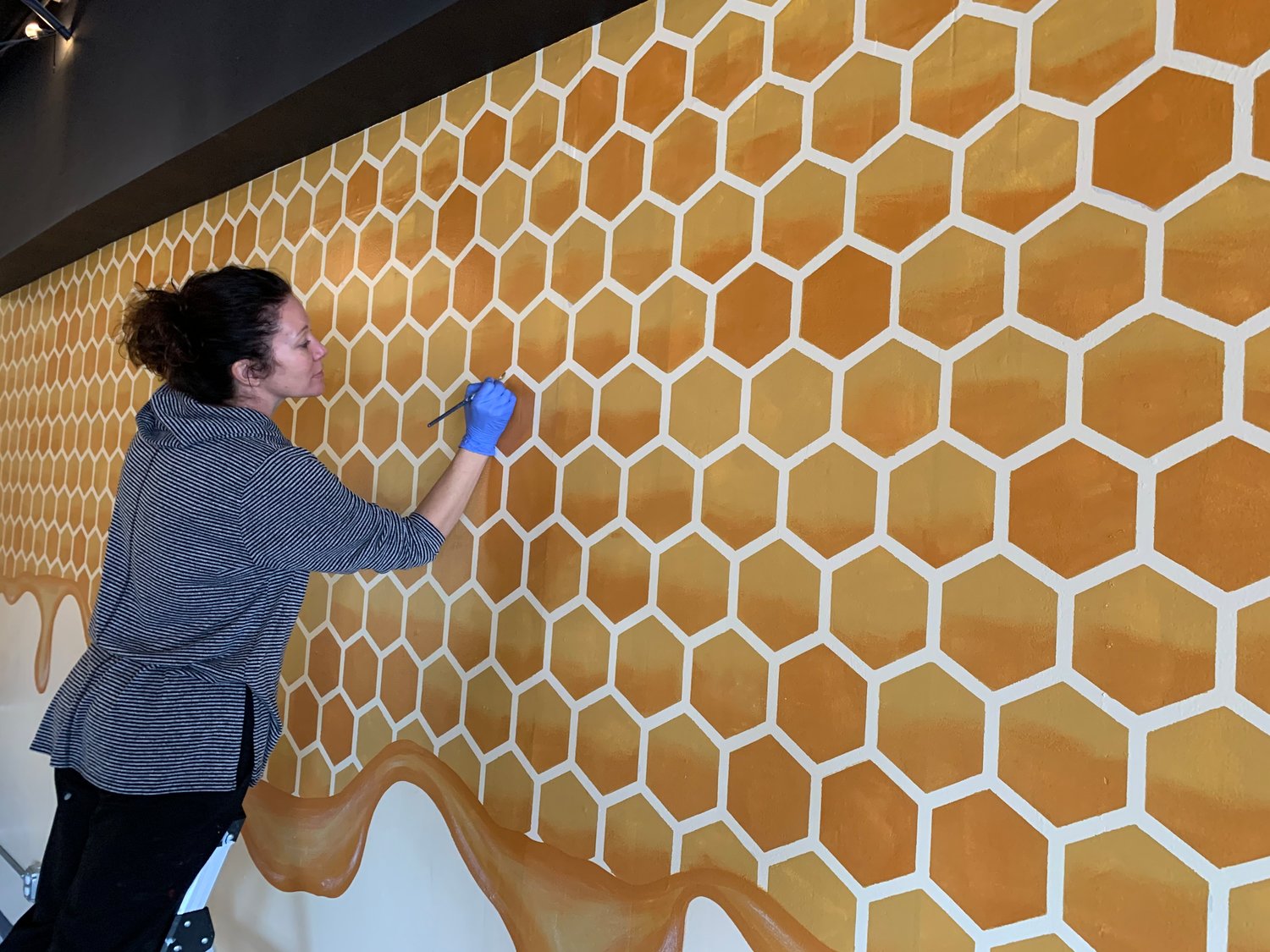 Christie Martin works on a honey-themed mural inside The Hive.