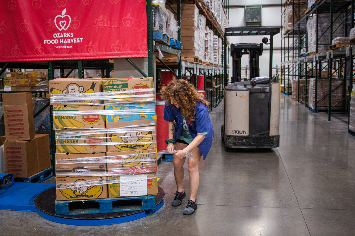 Ali Pool, volunteer coach at Ozarks Food Harvest, wraps a pallet of produce boxes.