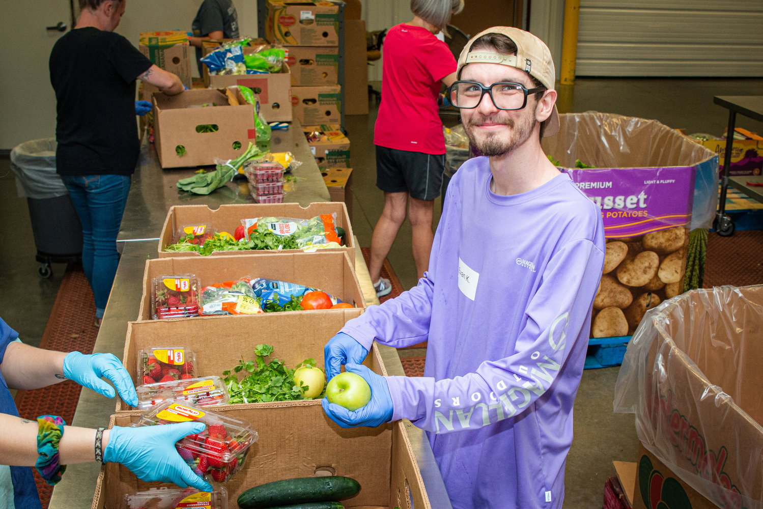 Evan Kozemski, volunteer at Ozarks Food Harvest, sorts and packs boxes of perishable food for distribution.