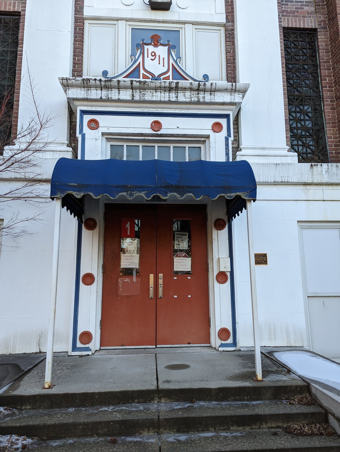 The front door of the historic Boyd Elementary still bears paper signage as a reminder of the bustle of activity that once took place there. The building is marked 1911 on the cartouche above the door. 