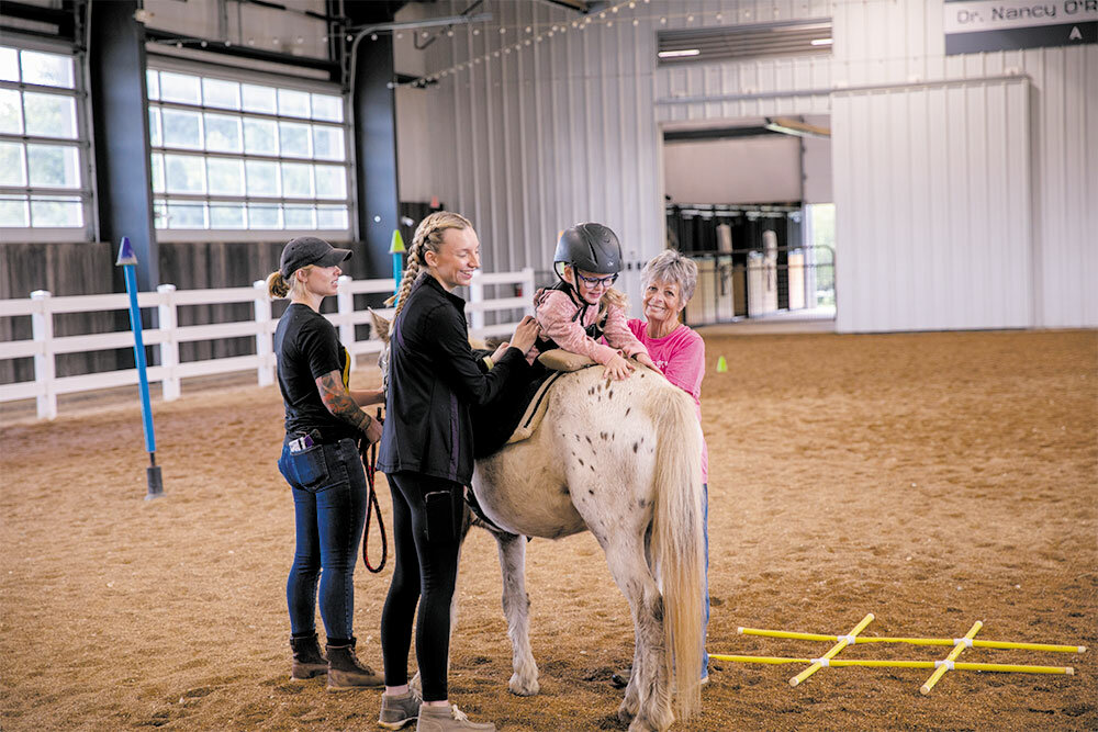 Dynamic Strides Therapy Occupational Therapist Kyra Treible performs hippotherapy with a young client named Renley. Assisting are Nora Walker, far left, and Randi Heard.